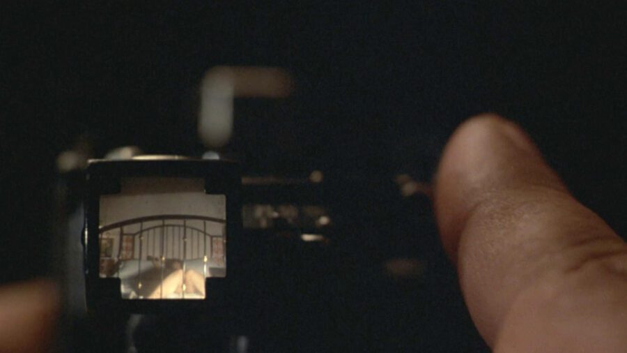 Sex, Power, and Rebellion: Symbolism in Tinto Brass Movies 7 Close-up of a camera viewfinder showing a woman in bed, with a man's finger on the shutter, highlighting secret desire and voyeuristic framing.