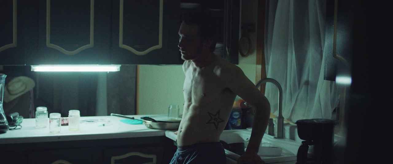 What Is Realism in Film? Definition, Examples & Key Styles 8 A shirtless man stands in a dim kitchen, lit only by a harsh overhead light