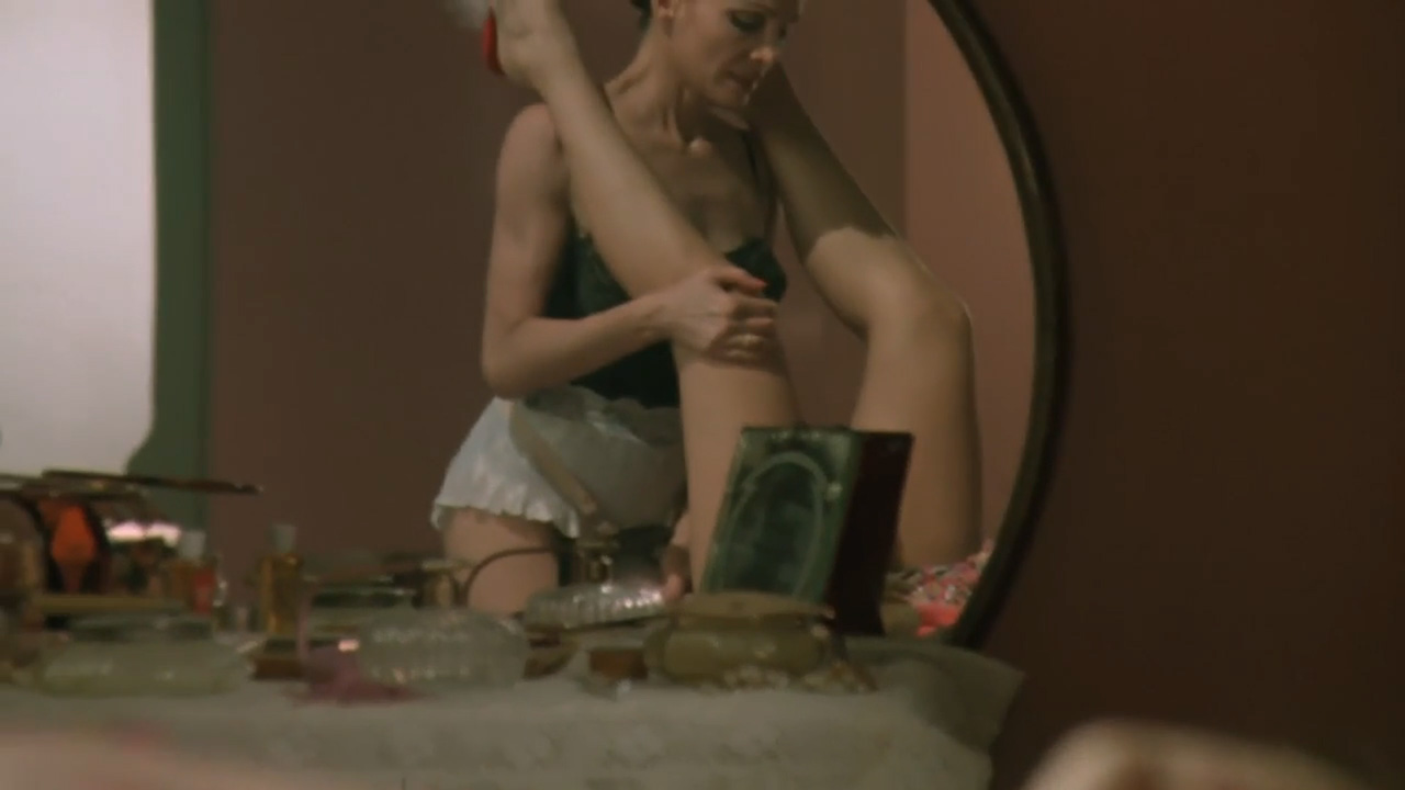 Sex, Power, and Rebellion: Symbolism in Tinto Brass Movies 5 Woman in lingerie seen through a mirror during an intimate moment, with her partner’s legs raised in the reflection, highlighting voyeuristic framing and indirect camera perspective.