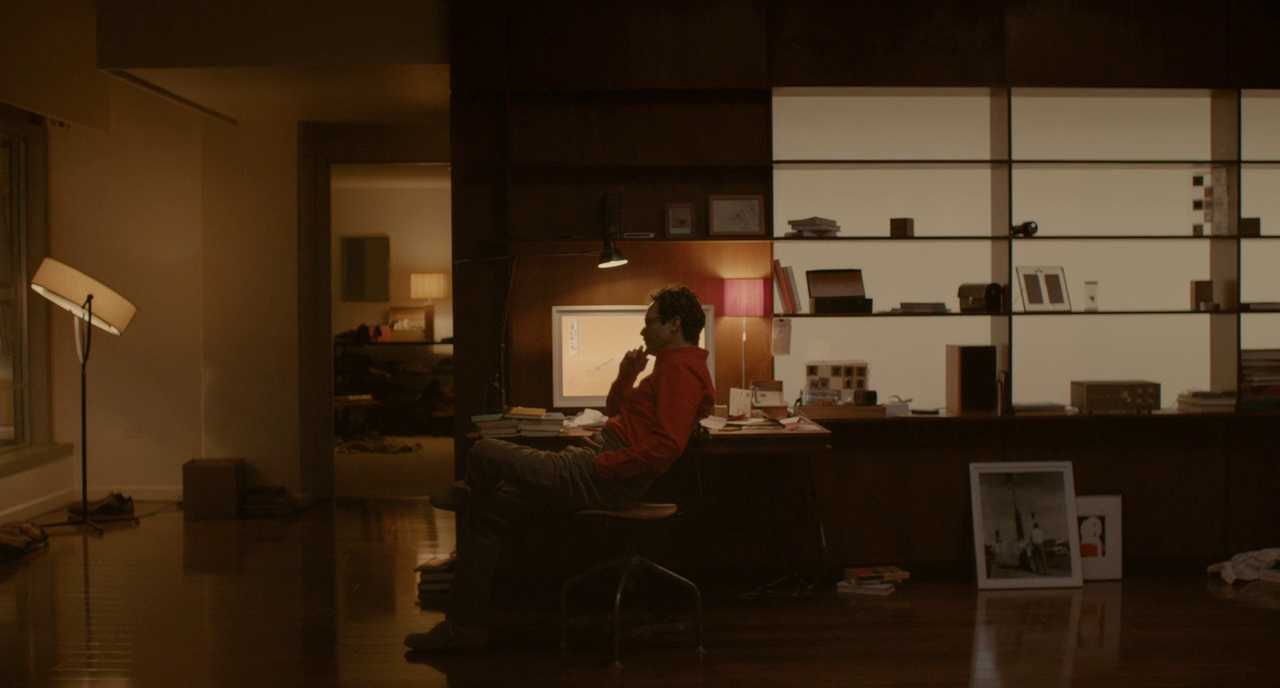 What Is Science Fiction? Definition & Film Origins Explained 16 A man in a red hoodie sits alone at his desk, looking at a computer screen in Her (2013).