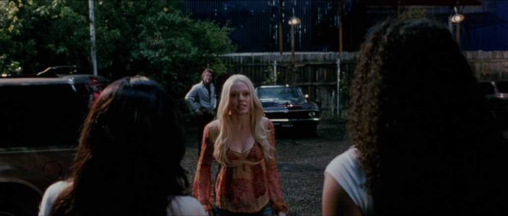 What Is a Grindhouse Movie? Definition & Origins 6 A tense nighttime standoff between a blonde woman and two others as a man watches from the background