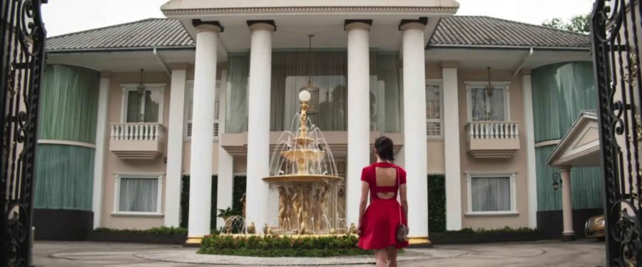 What is a Romcom? Definition, History & Tropes 7 Rachel stands in front of a mansion and gold fountain in Crazy Rich Asians (2018)