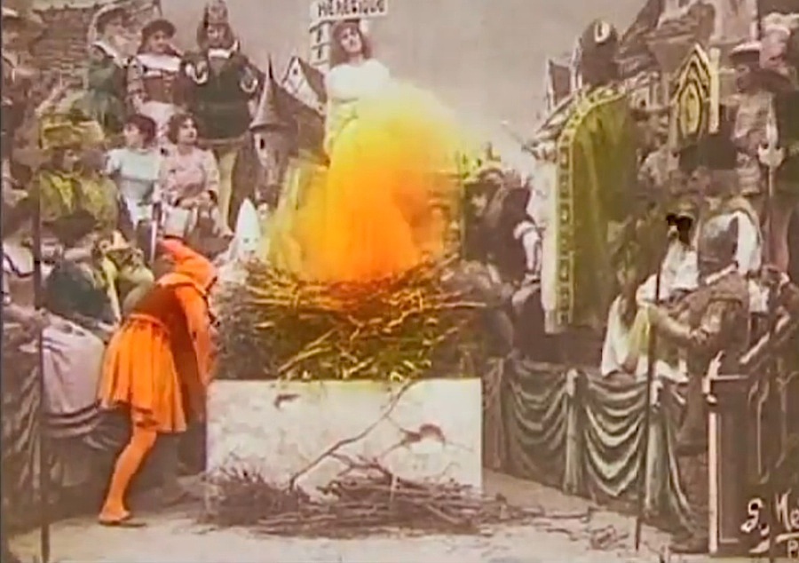 What Is a Biopic? Definition & Film Examples 2 Hand-colored silent film scene of Joan of Arc burning at the stake, surrounded by medieval onlookers in theatrical costumes.