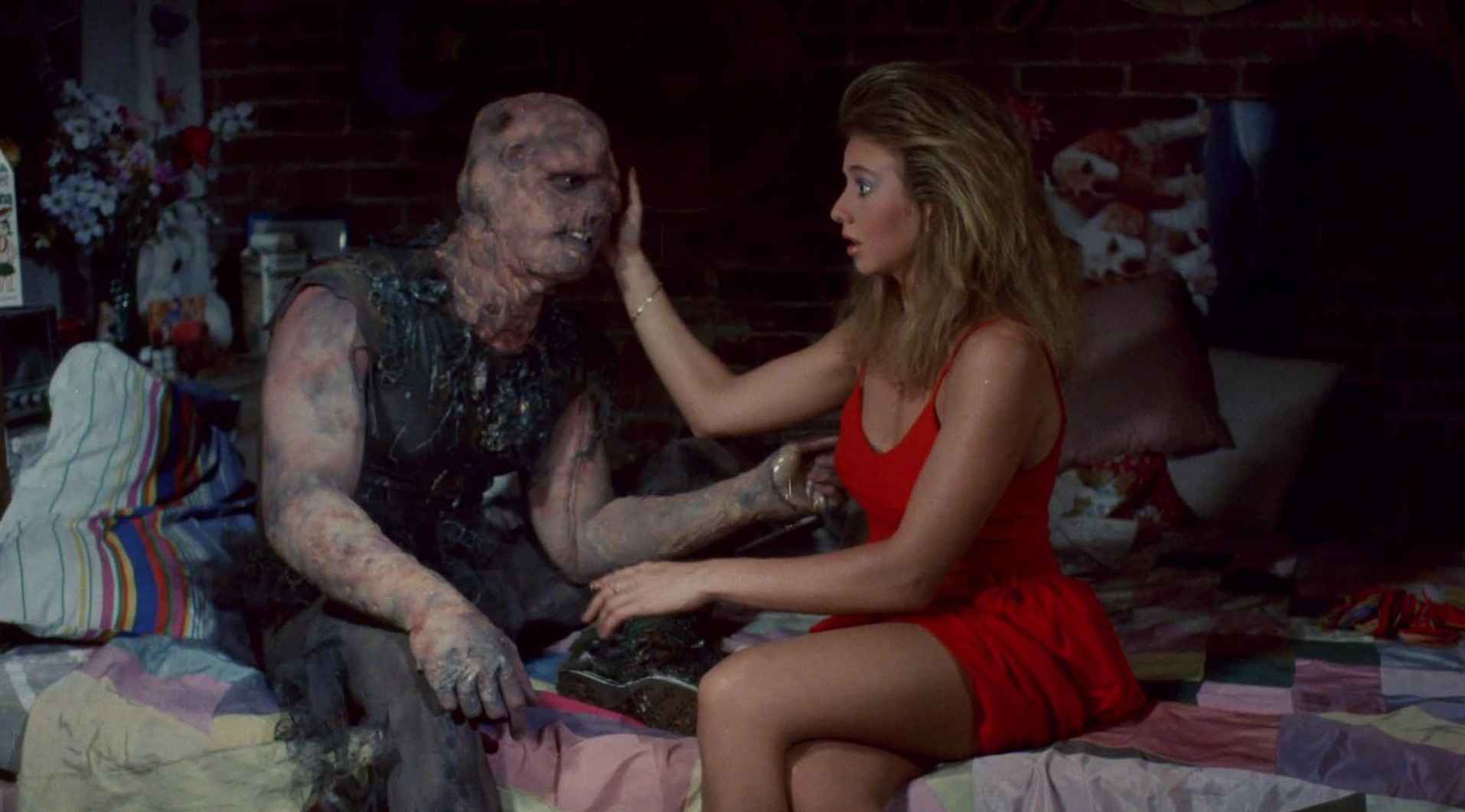 What Is a B-Movie? Definition & Film History 6 Disfigured mutant hero sits on a bed while a woman in a red dress gently touches his face.