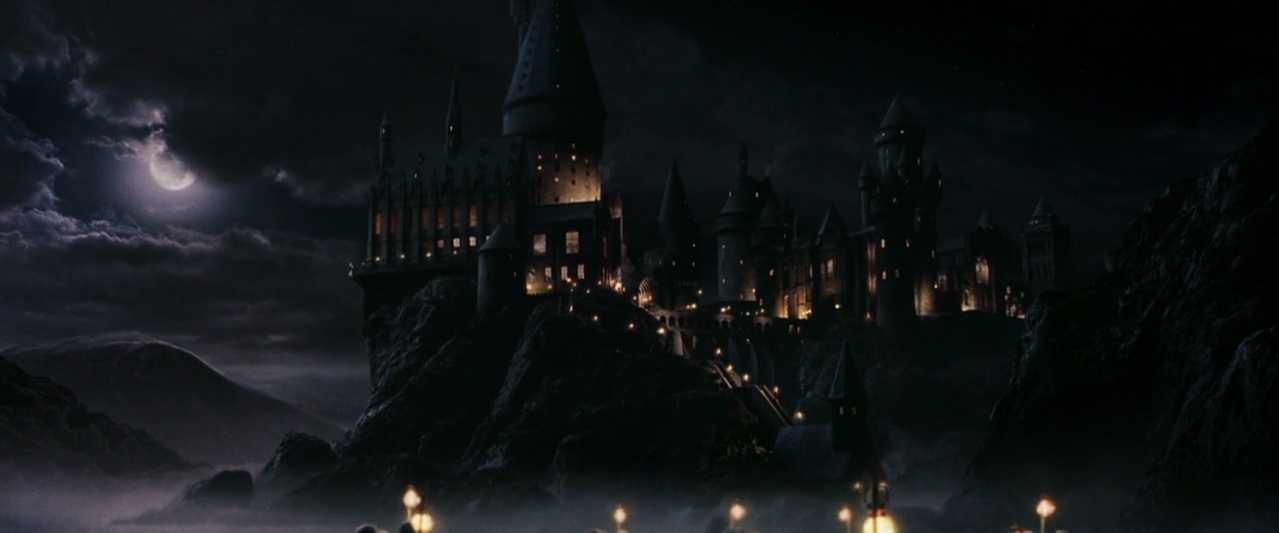 Similarities & Differences Between Science Fiction & Fantasy in Film Explained 5 Hogwarts Castle lit up at night under a cloudy moonlit sky
