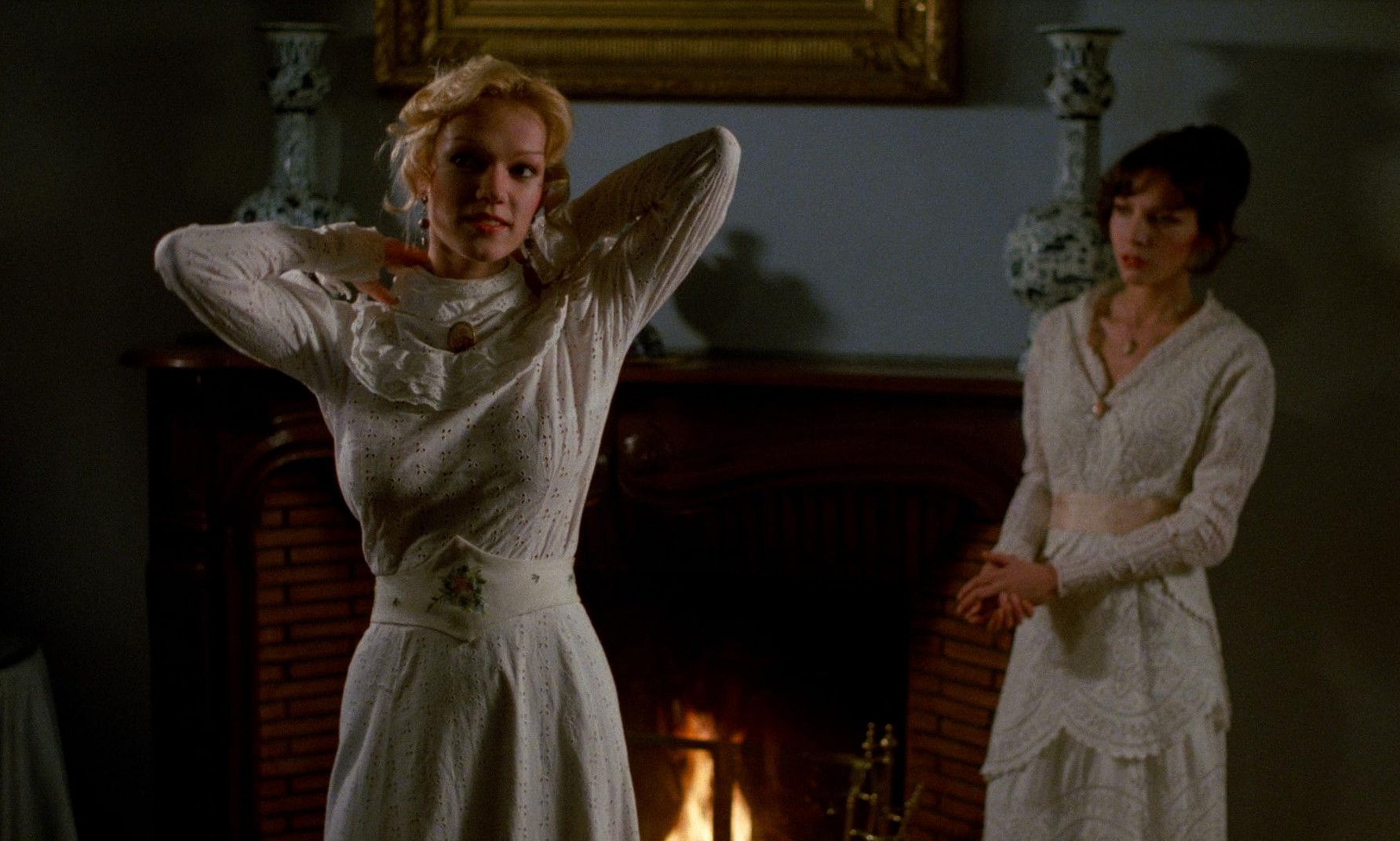 What Are Sexploitation Films? Definition, Movies & Global Impact 13 Brigitte Lahaie stands by a fireplace in a white dress while another woman watches in Fascination (1979)