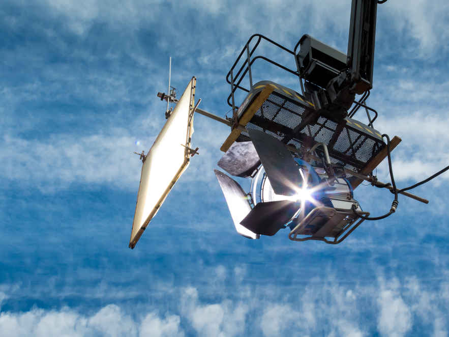 What is a Gaffer? Job Description, Skills & Training Path 2 Large HMI light and bounce board rigged on a crane against blue sky
