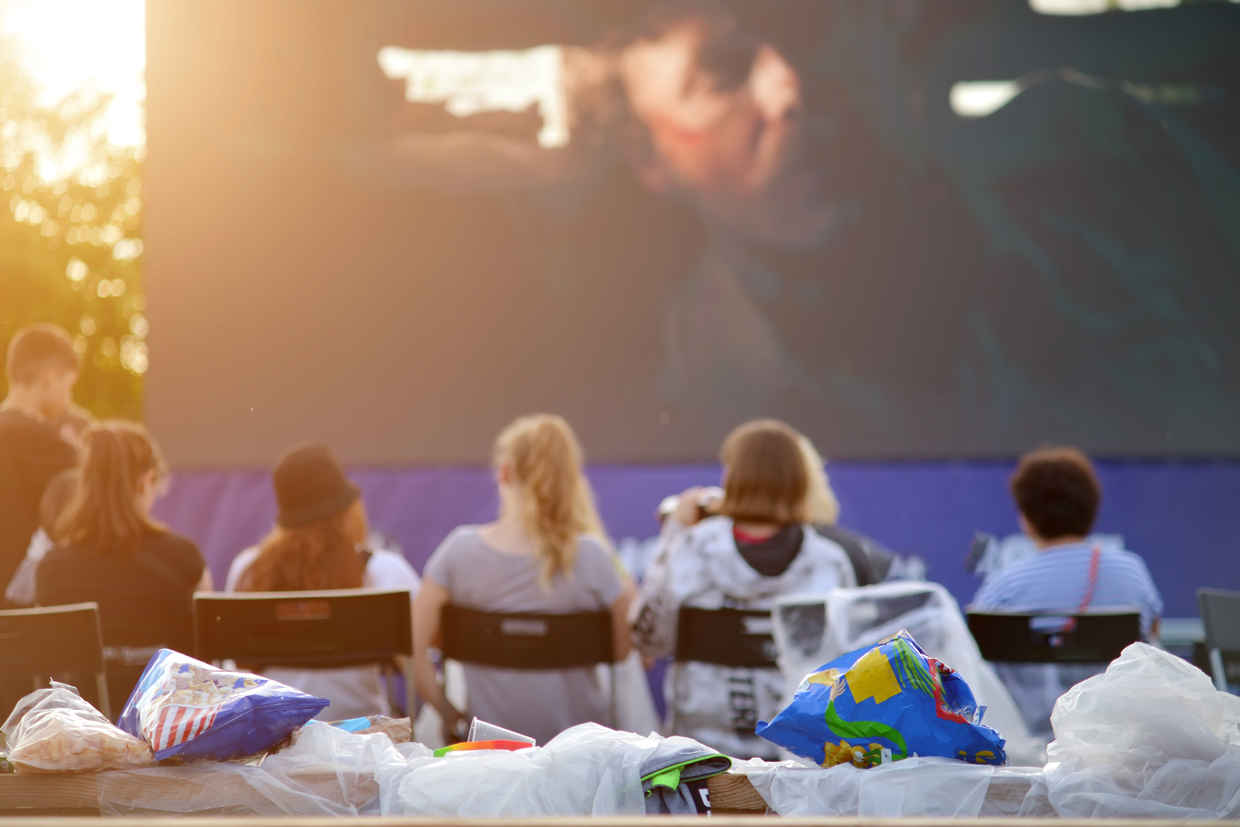 What Does a Movie Critic Do? Job & Career Guide 4 People sitting in chairs watching a movie outside with snacks and plastic bags in front