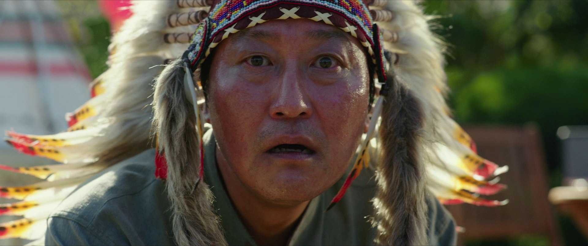 What Is Black Comedy? Definition, Themes & Top Picks 2 A man in a Native American headdress stares in disbelief during a backyard celebration