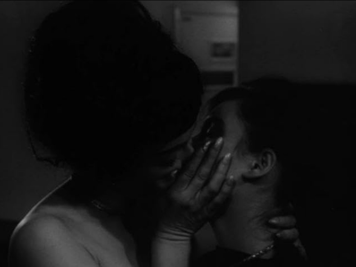 What Are Sexploitation Films? Definition, Movies & Global Impact 6 Two women kiss in a dimly lit room in a scene from Sin in the Suburbs (1964).