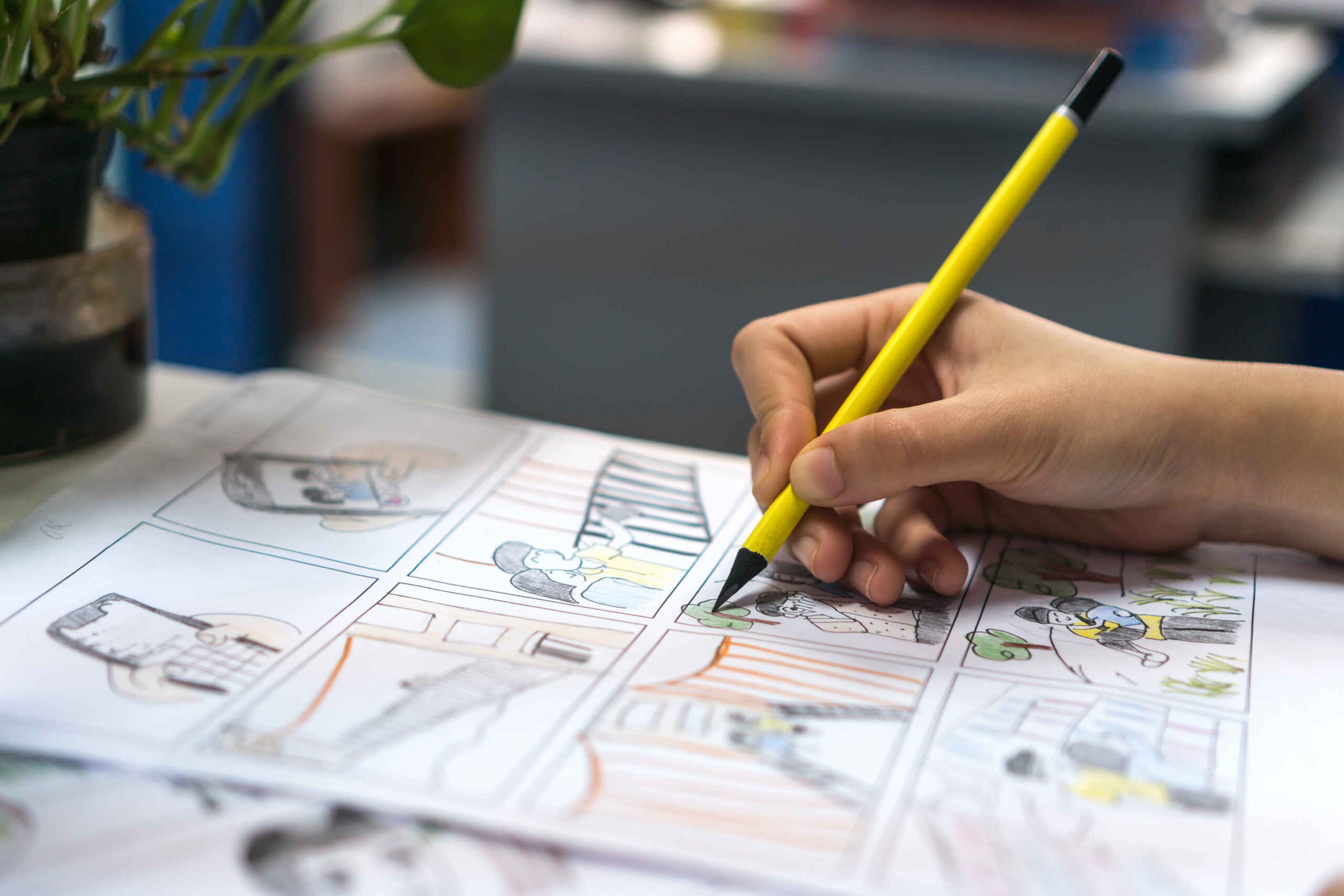 What Is a Storyboard Artist? Job Description & Definition 3 Close-up of hand drawing a colored storyboard with pencil, showing cartoon characters and scene layout