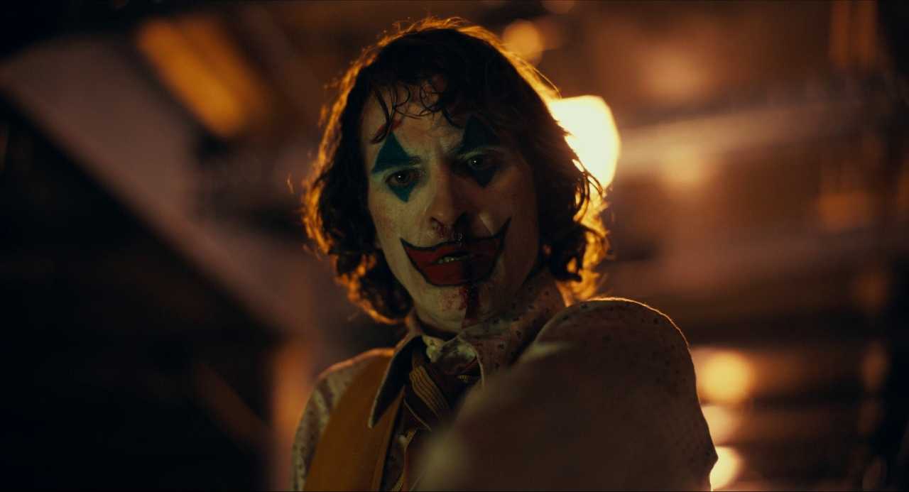 What Does a Cinematographer Do? Job Description & Real DP Examples 2 Close-up of Arthur Fleck in full Joker makeup, lit from behind with warm lights and framed in a tight shot.