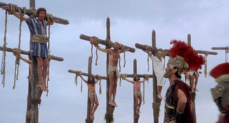 What Is Black Comedy? Definition, Themes & Top Picks 3 A group of men are crucified on wooden crosses, singing cheerfully as Roman guards walk by