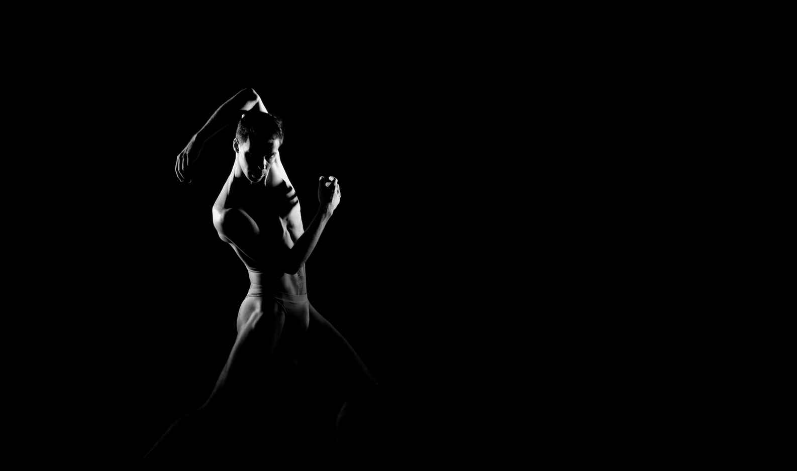 Types of Photography: Genres, Styles & Techniques Explained 21 Black and white image of a male dancer lit from the side against a dark background