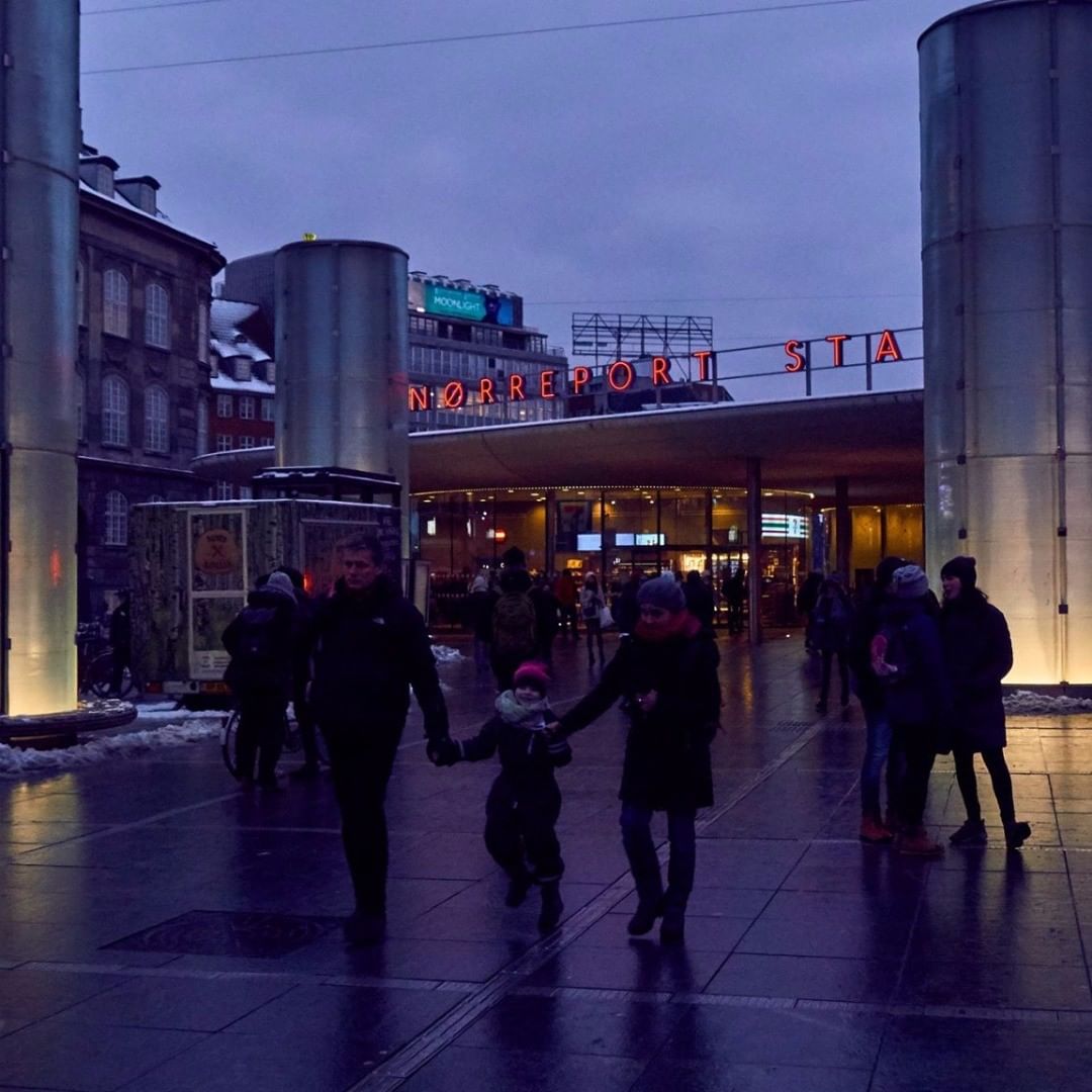What Is Magic Hour in Photography? What It Is & How to Shoot It 8 People walking outside Nørreport Station in Copenhagen during blue hour, with cool sky and warm building lights reflected on the ground