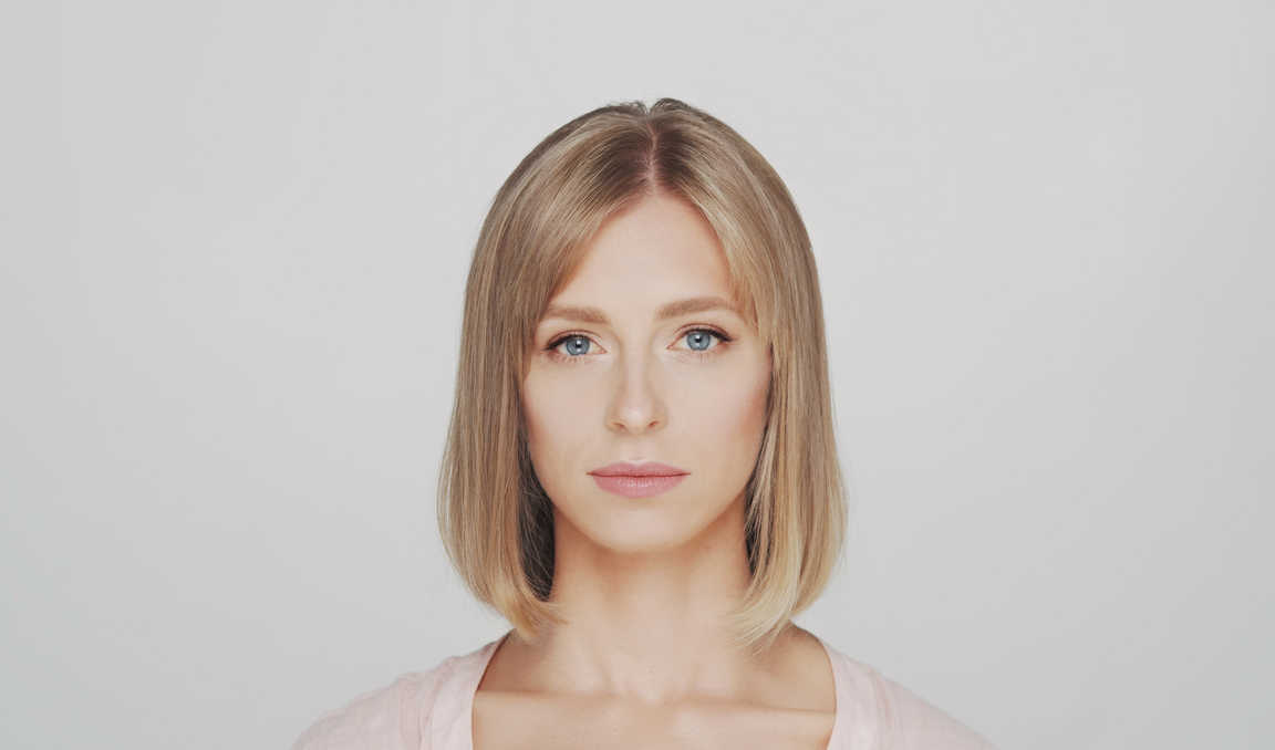 Portrait Lighting Setup Guide: Rembrandt, Loop & Beyond 18 Woman’s face lit evenly with clamshell lighting on a neutral background.