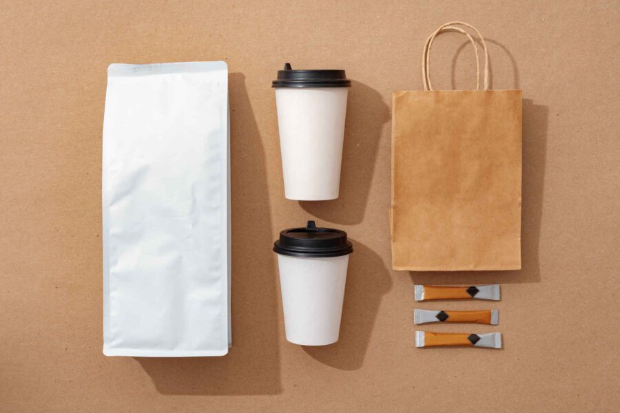 Types of Photography: Genres, Styles & Techniques Explained 5 Flat lay of coffee packaging, to-go cups, paper bag, and sugar sticks on brown background