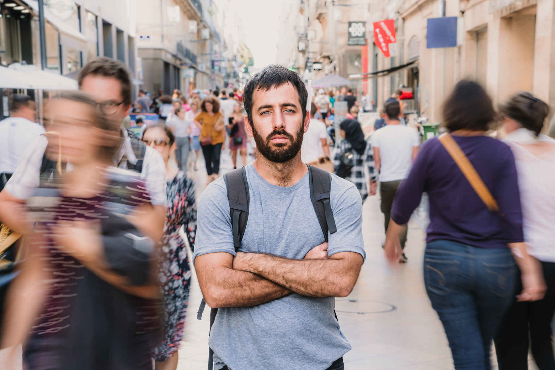 What Is Long Exposure Photography? Definition & Guide 3 Man standing still in sharp focus while blurred people move around him on a crowded street, captured with long exposure.