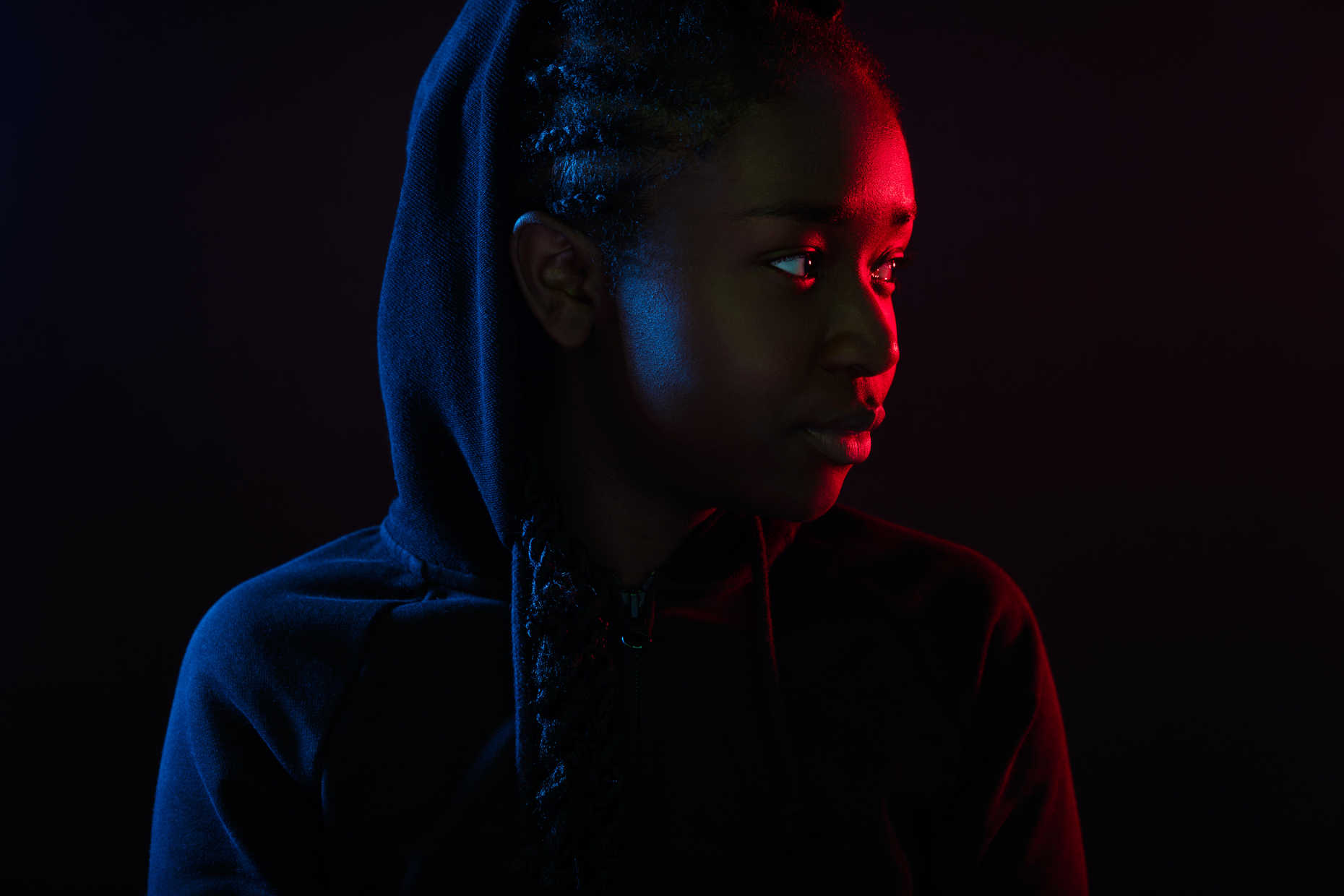 Portrait Lighting Setup Guide: Rembrandt, Loop & Beyond 20 Woman’s face lit with red and blue cross lighting against a black background.