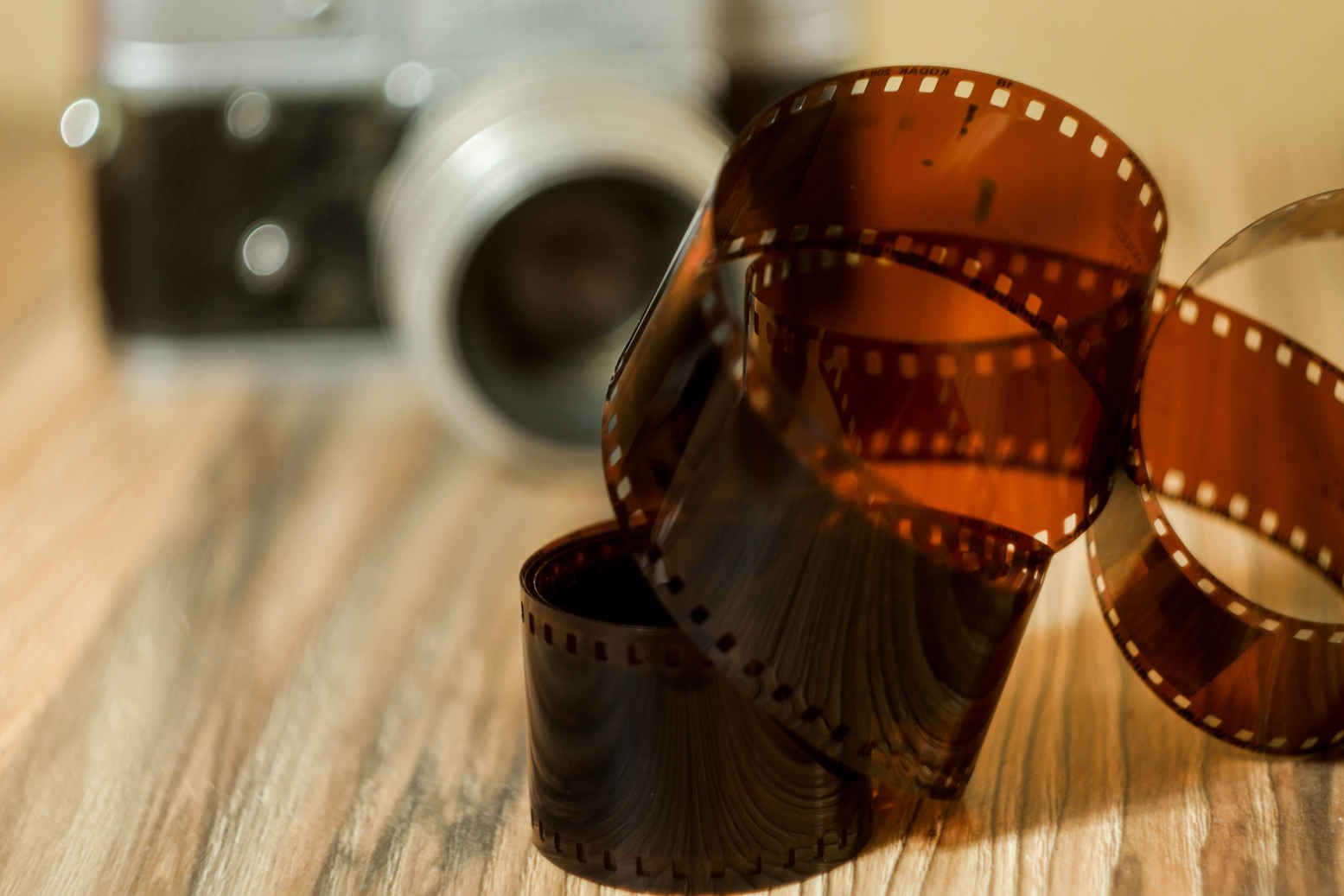 Types of Photography: Genres, Styles & Techniques Explained 30 Close-up of film roll on wooden surface with blurred vintage camera in background