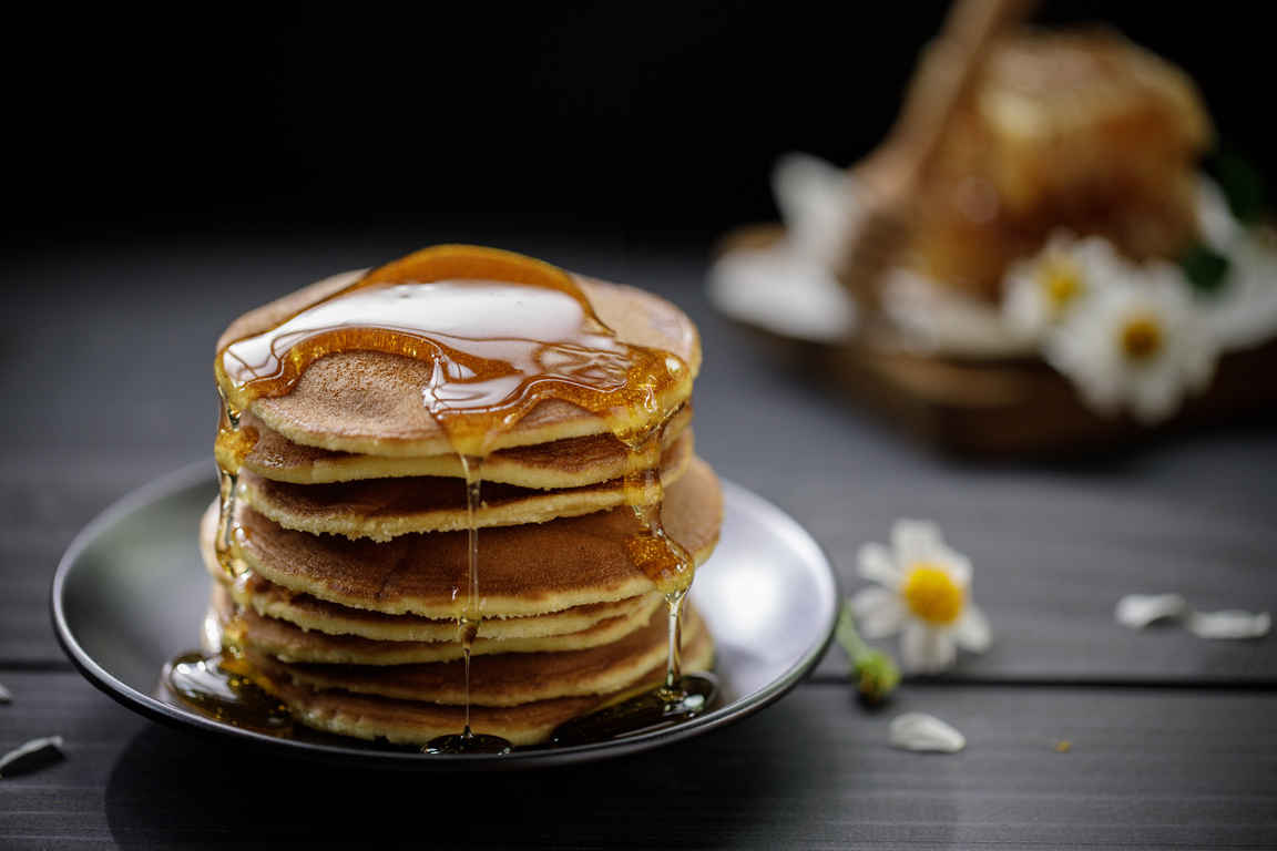 Types of Photography: Genres, Styles & Techniques Explained 10 Stack of pancakes with honey dripping down, styled with flowers and honeycomb in background