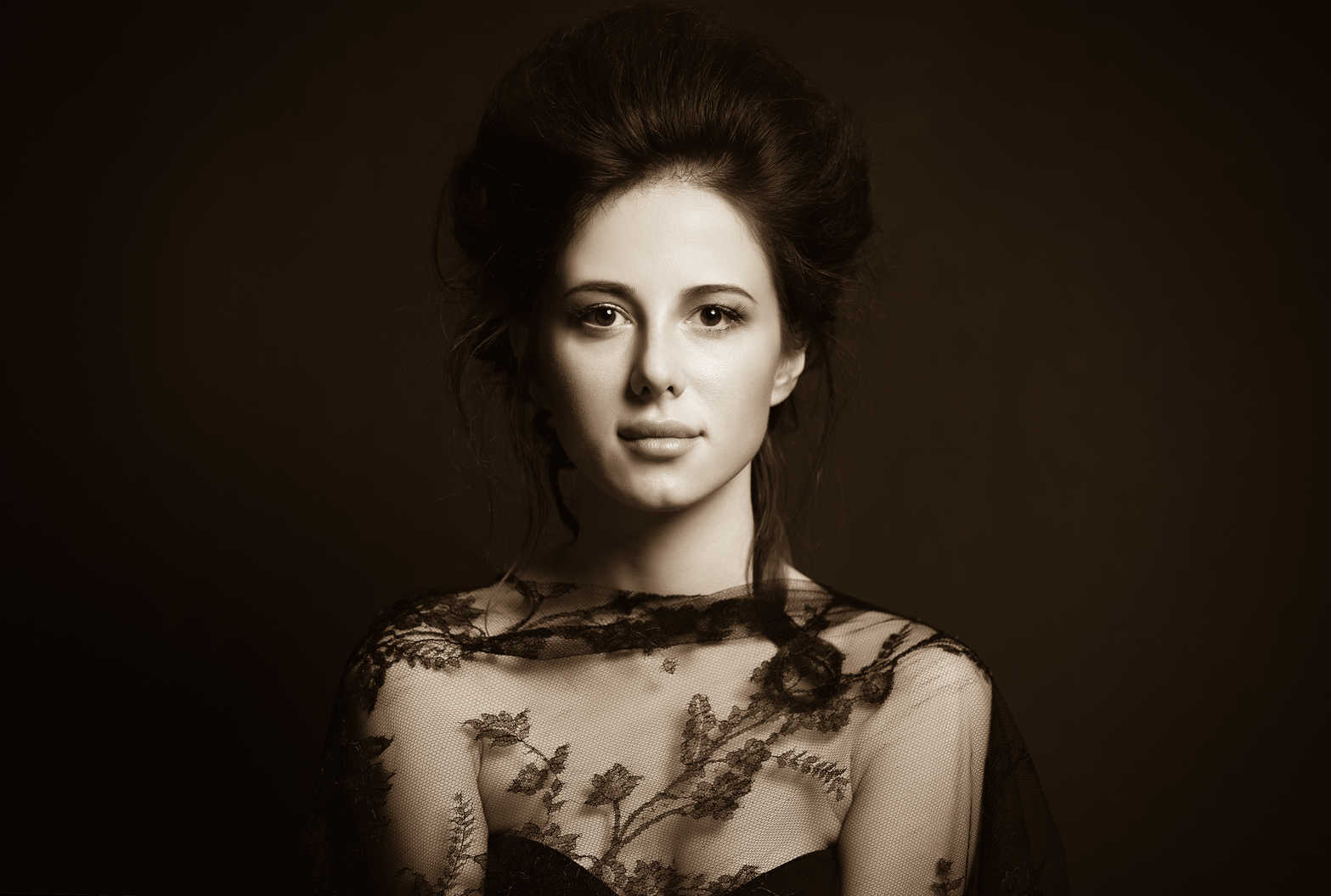 Portrait Lighting Setup Guide: Rembrandt, Loop & Beyond 2 Portrait of a woman with auburn hair styled in loose waves, wearing a sheer black lace top, lit with loop lighting that creates a soft shadow of the nose on the cheek, set against a dark brown background.