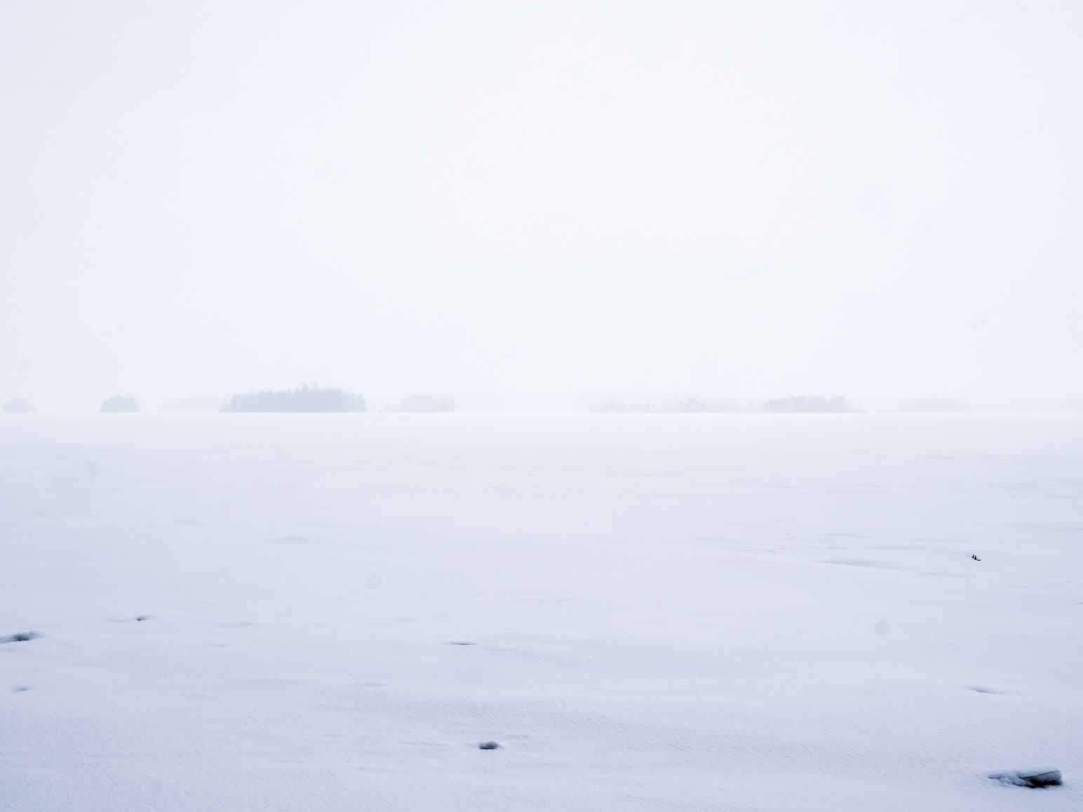 Types of Photography: Genres, Styles & Techniques Explained 25 Minimal winter photo of a frozen lake in Sweden during a whiteout, with no visible horizon and soft gray tones throughout.