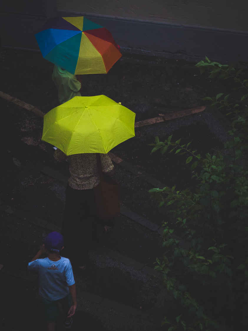 Types of Photography: Genres, Styles & Techniques Explained 16 Overhead view of two people with colorful umbrellas and a child walking on a dark street