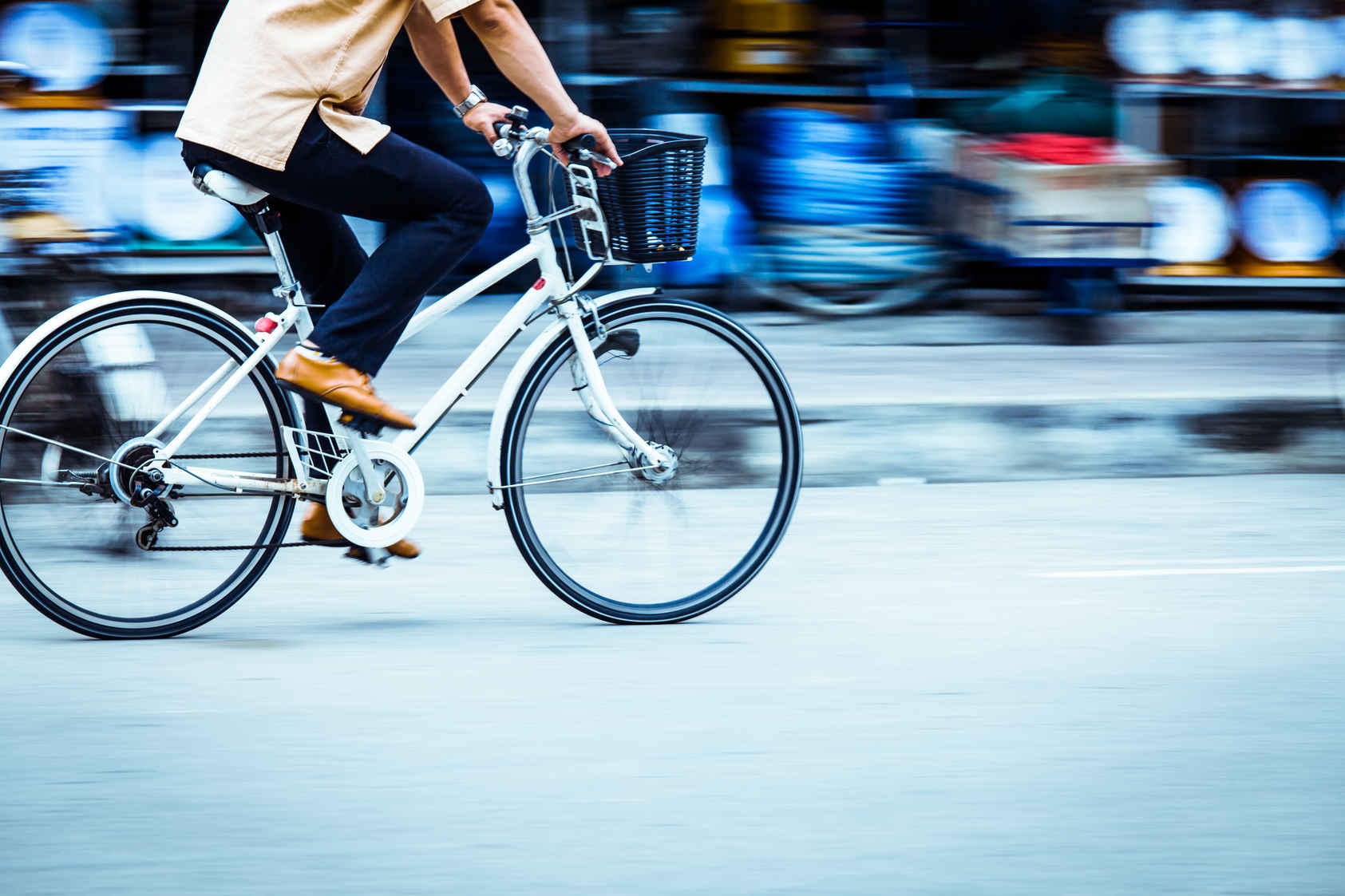 Types of Photography: Genres, Styles & Techniques Explained 36 A person rides a white bicycle while the background blurs with streaks of motion, showing the panning photography technique.