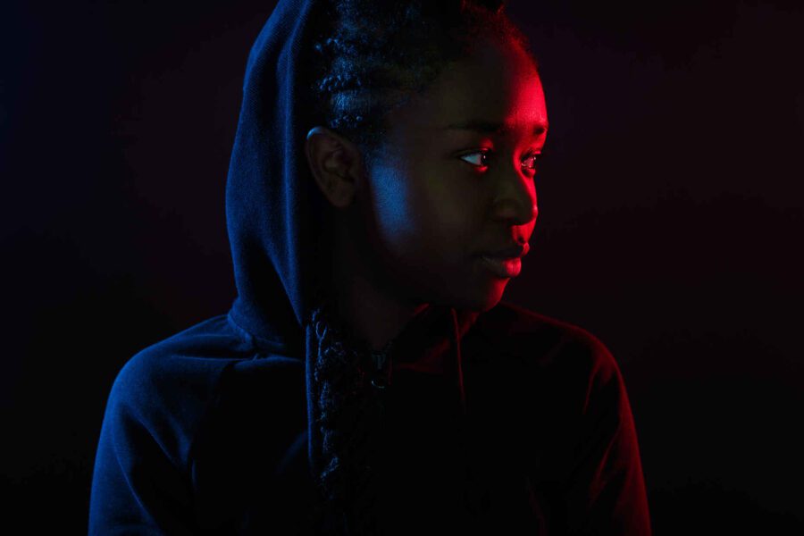 Types of Photography: Genres, Styles & Techniques Explained 12 Portrait of a person in hoodie lit with red and blue light against a dark background