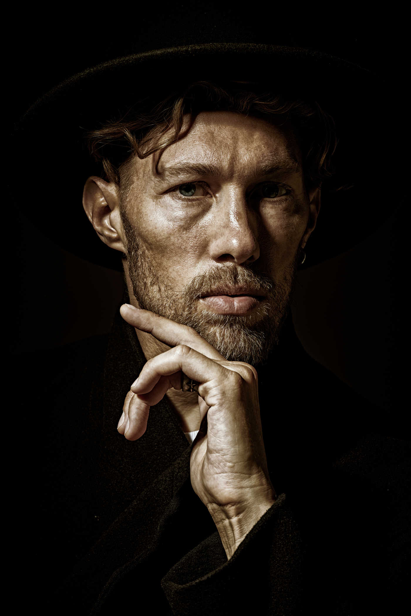 Portrait Lighting Setup Guide: Rembrandt, Loop & Beyond 7 Portrait of a man lit with Rembrandt lighting showing a triangle of light under one eye and shadows on the other side of the face against a dark background.