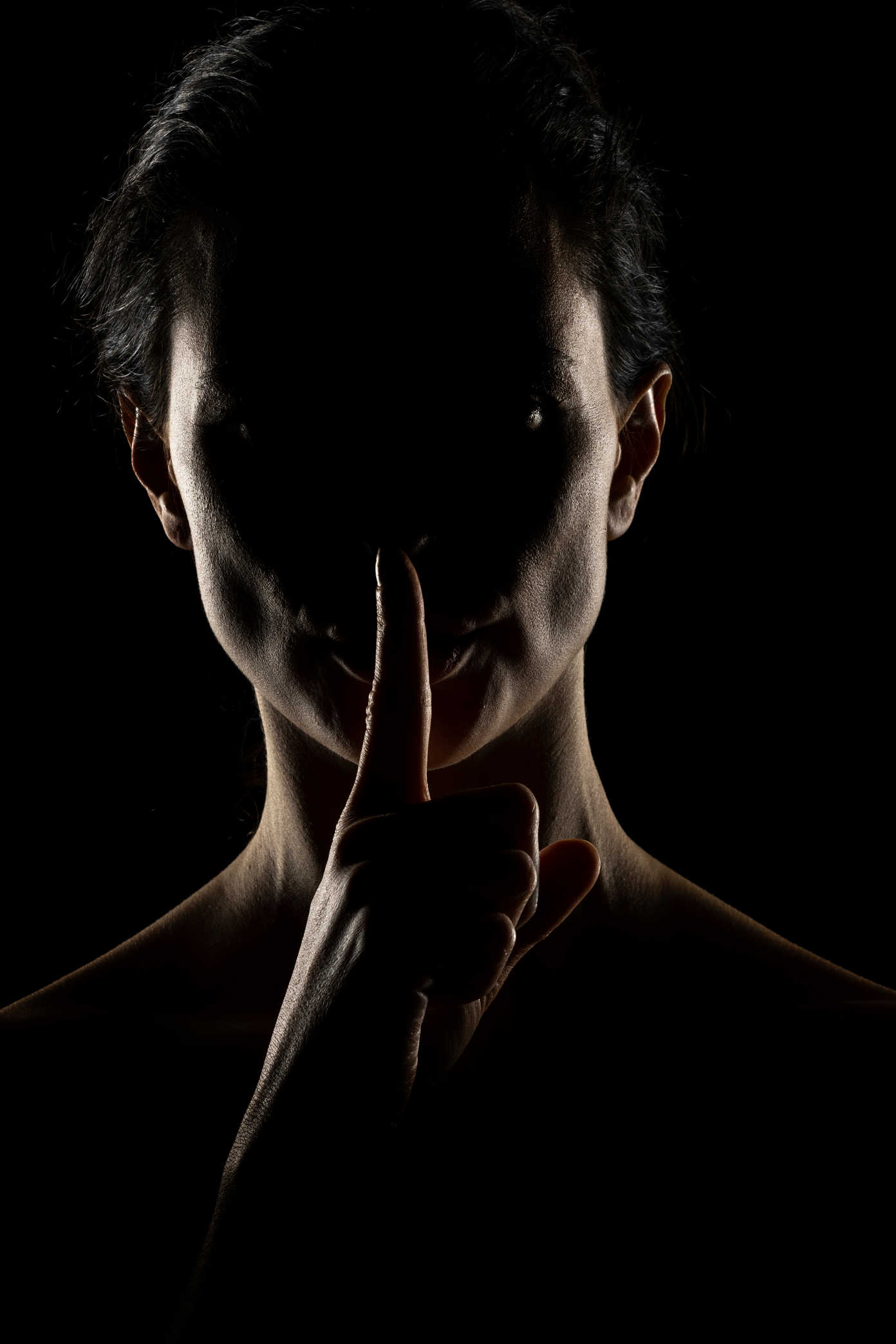 Portrait Lighting Setup Guide: Rembrandt, Loop & Beyond 15 Silhouetted portrait with rim lighting outlining the face and hand against a black background.
