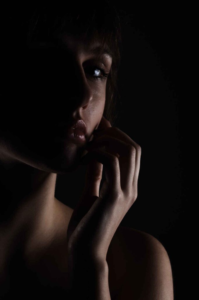 Types of Photography: Genres, Styles & Techniques Explained 43 Portrait of a woman lit with short lighting. The far side of her face is lit, while the near side remains in deep shadow.