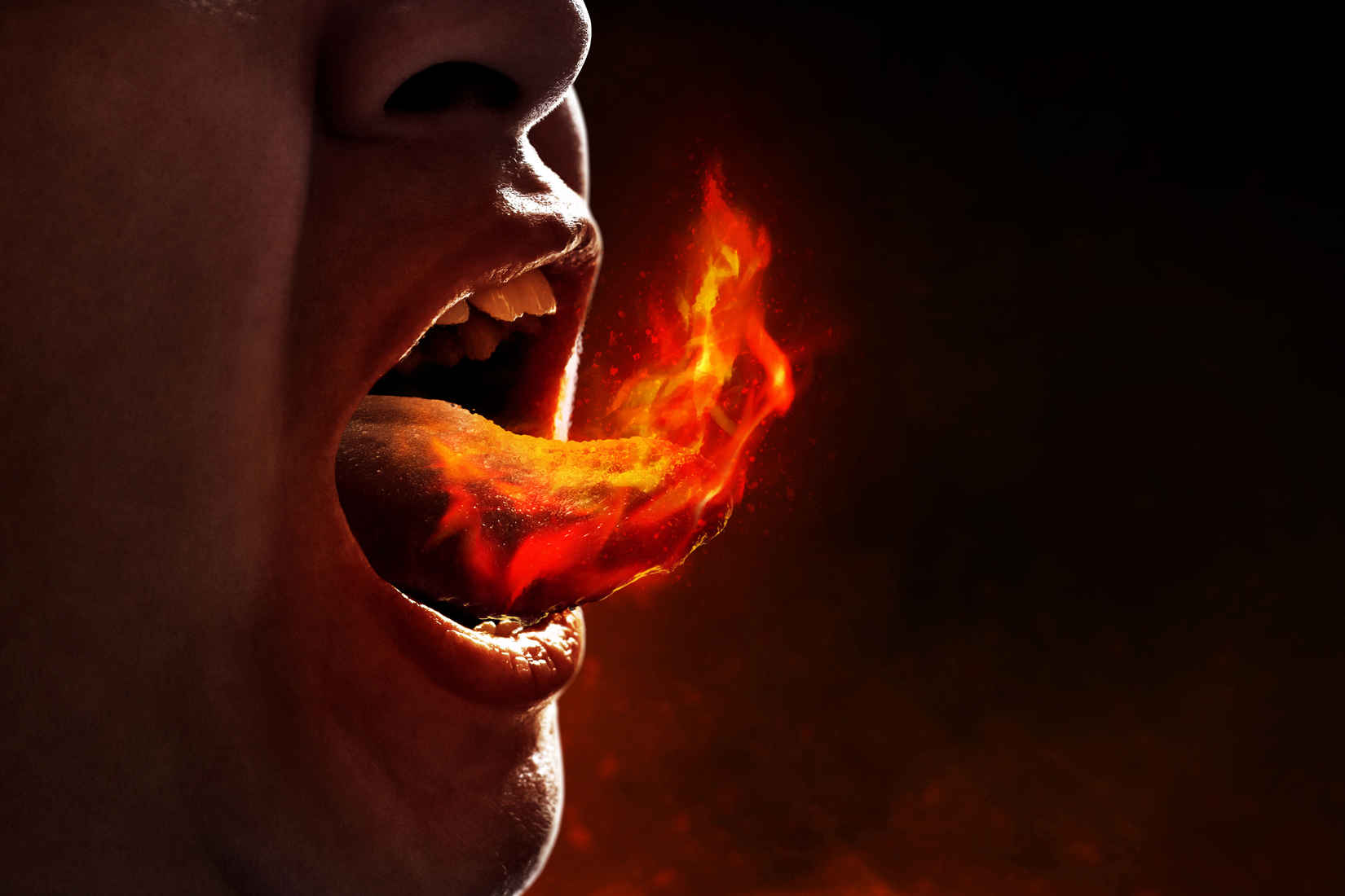 What Is Conceptual Photography? Definition, Style & Examples 3 Close-up of a person’s open mouth with a glowing flame rising from their tongue, symbolizing extreme heat or spiciness.
