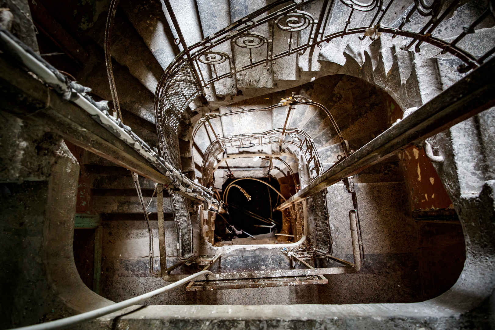 Types of Photography: Genres, Styles & Techniques Explained 18 Looking down a decayed spiral stairwell in an abandoned building with broken railings and debris