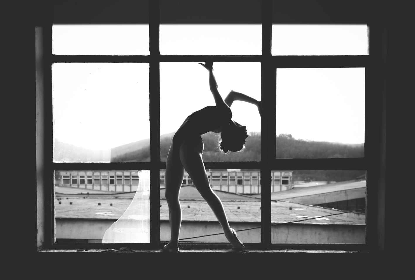 Types of Photography: Genres, Styles & Techniques Explained 24 Black and white image of a dancer posing in silhouette against large industrial window