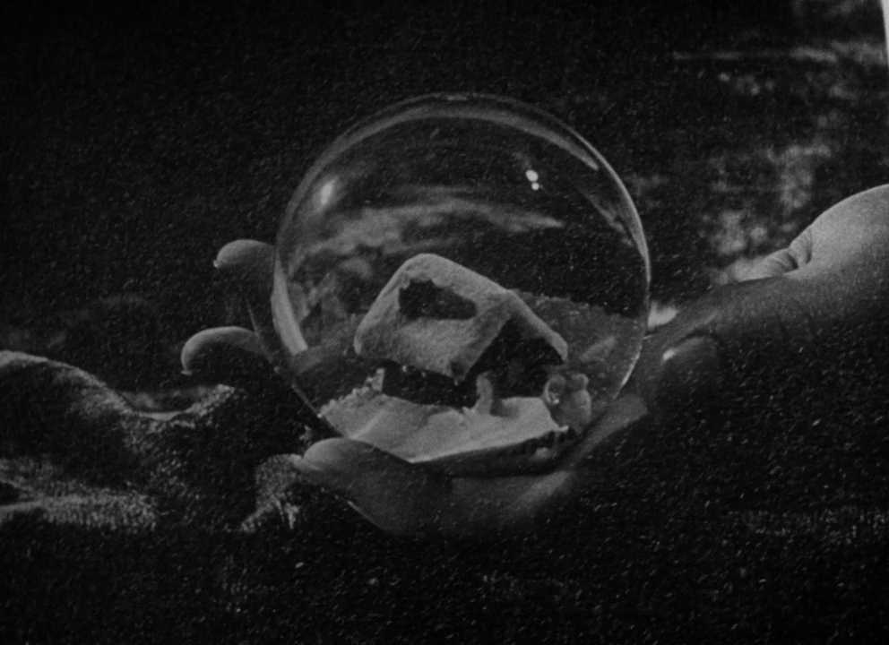 What Is the Difference Between Plot and Story? 5 A hand holds a glass snow globe showing a small house in the snow, moments before it falls.