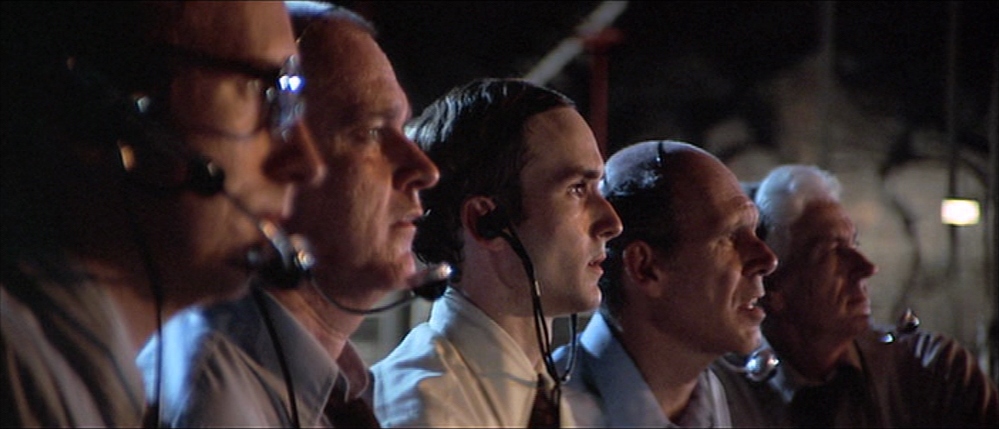 What is a Medium Close‑Up Shot (MCU)? Definition 7 Five men wearing headsets, framed side by side in a medium close-up; the center man is sharp while others fade into soft focus
