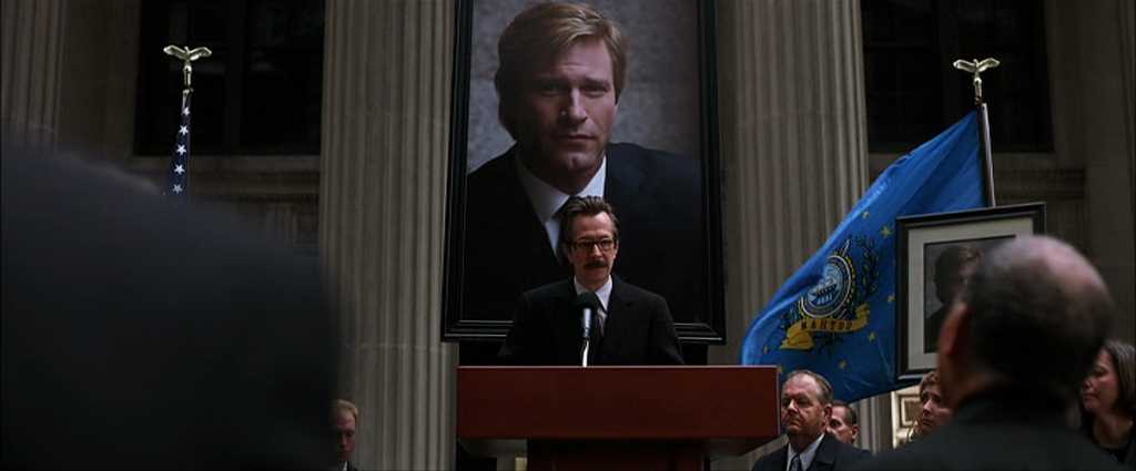 Falling Action in Stories: Meaning & Film Examples 5 Commissioner Gordon gives a speech in front of a large portrait of Harvey Dent during a formal memorial ceremony.