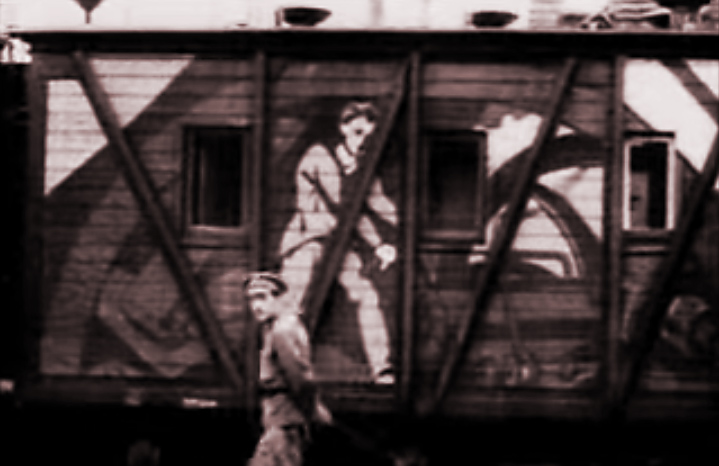 What Is Agitprop? How Soviet Cinema Used Montage for Propaganda 2 A train car painted with large stylized images of workers, including a man sitting and another figure behind machinery, with a person walking nearby.