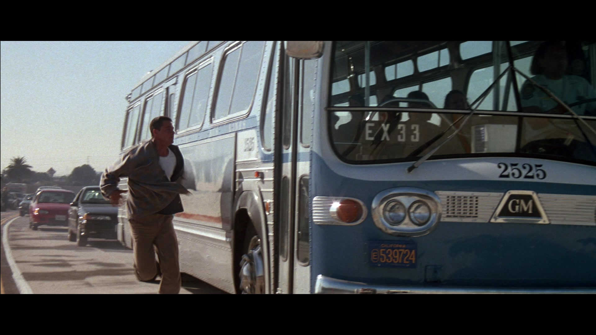 Rising Action in Film: Meaning, Function & Examples 6 A man runs beside a city bus on a highway as it begins to speed up, with traffic in the background