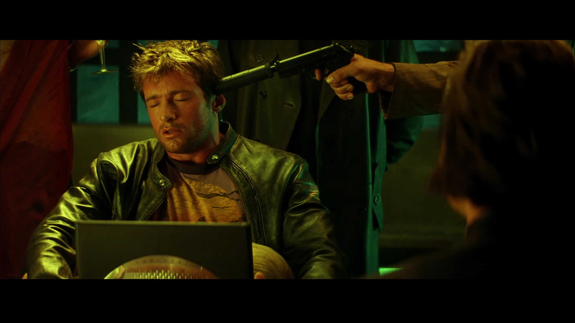 What Is a Dead Metaphor? When Imagery Goes to Die 3 A man is forced to hack a laptop under pressure, with a gun to his head and a woman performing oral sex, creating a scene of extreme stress.