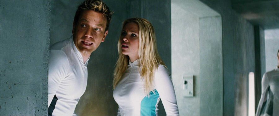 What is Plato's Allegory of the Cave? Meaning, Films & Philosophy Explained 3 Two characters in white uniforms hide behind a wall inside a futuristic facility, looking alarmed