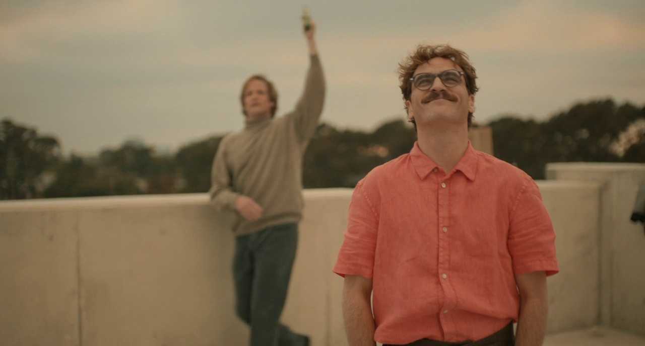 What Is a Monochromatic Color Scheme? Definition & Film Examples 3 Scene from Her with Theodore in a coral shirt smiling on a rooftop, surrounded by soft red and beige tones in a warm monochromatic palette