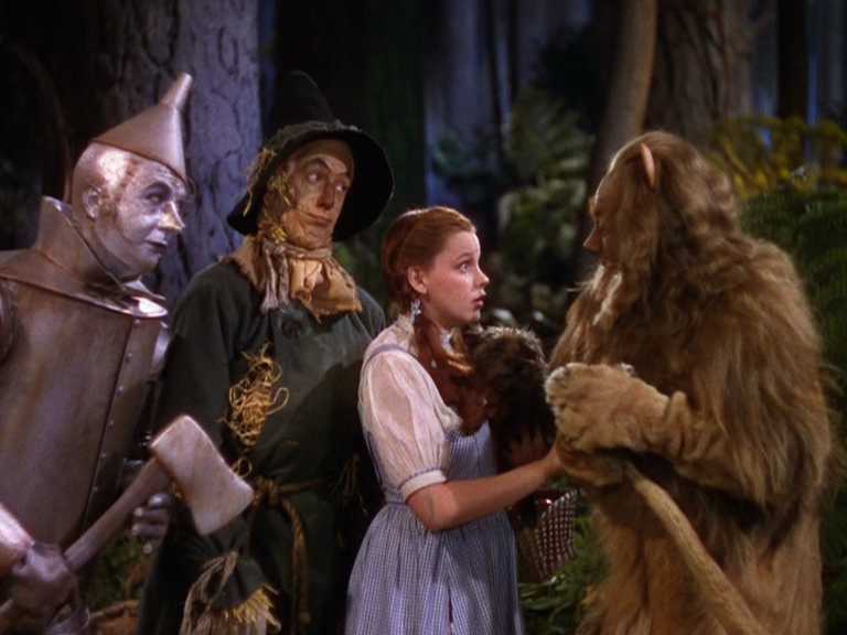 What and When Was the Golden Age of Hollywood? 4 Dorothy, the Scarecrow, Tin Man, and Cowardly Lion stand together in a vivid Technicolor forest scene, dressed in bright, detailed costumes.