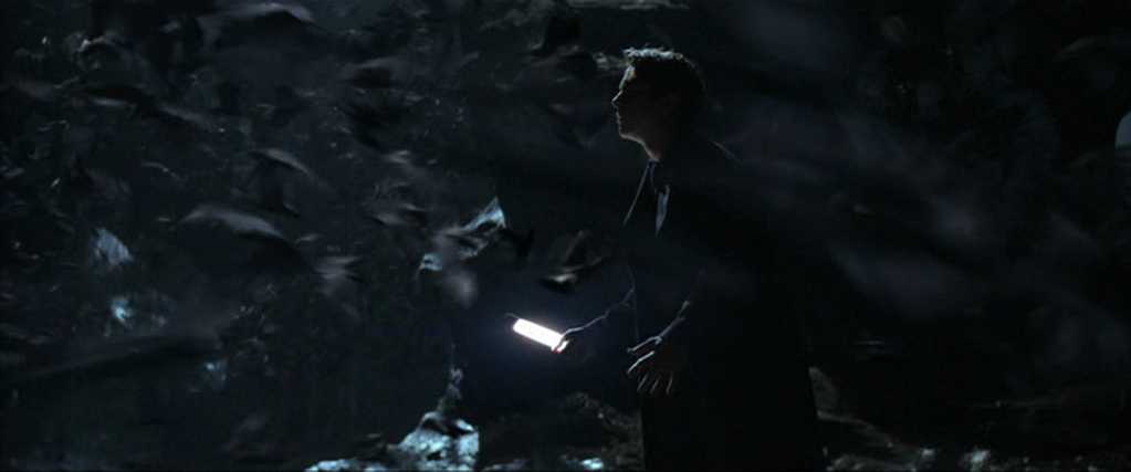 Origin Stories in Film: Types, Structure, and Meaning 2 Bruce Wayne stands in a dark cave holding a light, surrounded by a swirling swarm of bats.