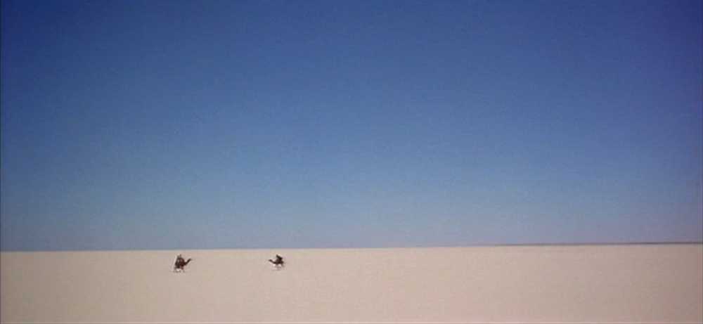 Settings Ideas and Examples for Film Scenes 9 Two distant figures on camels cross a vast white desert under a deep blue sky with no visible landmarks