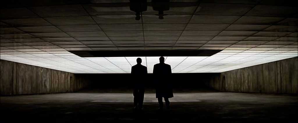 What Is an Alter Ego? Definition, Meaning & Film Examples 4 Bruce Wayne and Lucius Fox walk through a wide underground room lit by a glowing ceiling, with no Batman equipment in sight