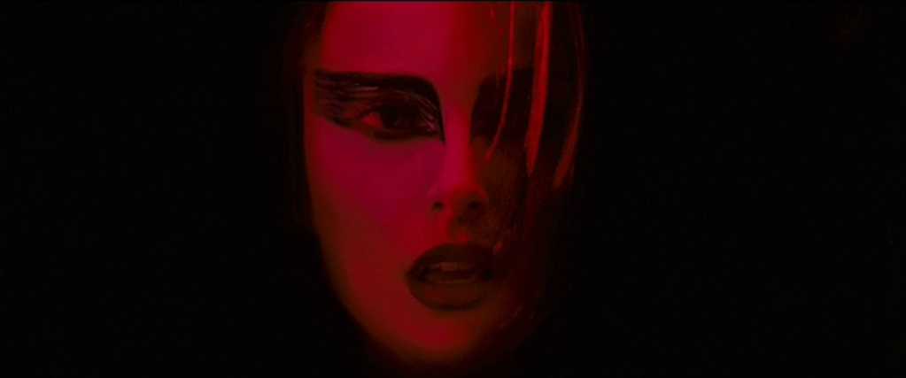 What Is a Color Palette? How to Use it in Film (+Free Planner) 10 A close-up of Nina's face lit in deep red, with dramatic eye makeup and shadows surrounding her.