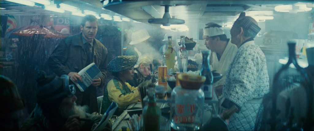 What Is World Building in Movies? Definition, Meaning & Examples 2 A rainy street-side noodle bar filled with people, neon lights, steam, and bottles, with Deckard standing among them holding a book.